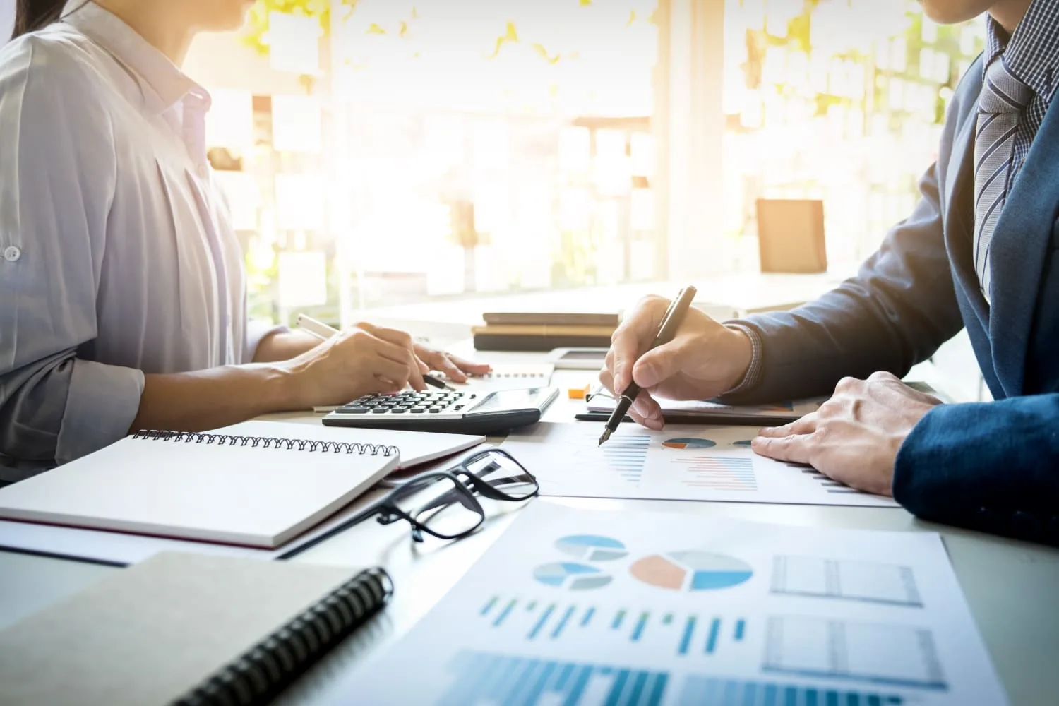 Two advisors reviewing financing paperwork with a calculator and printed charts