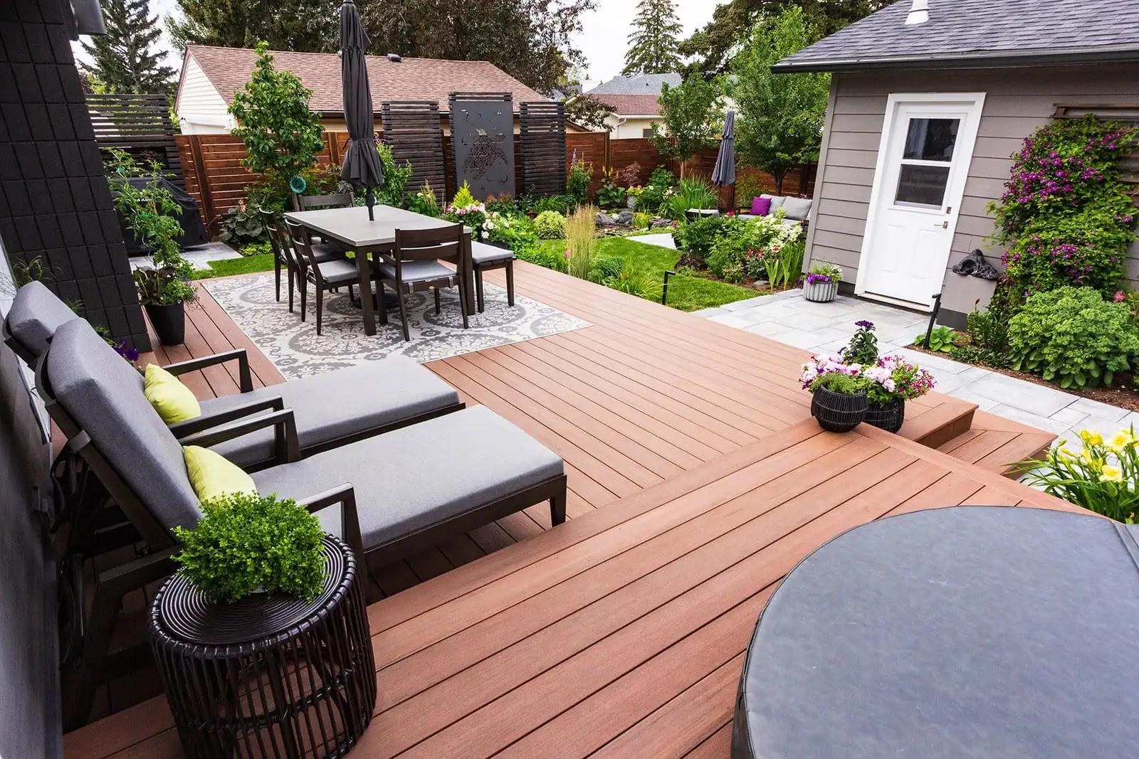 Backyard composite deck with lounge chairs, umbrella dining set and garden beds
