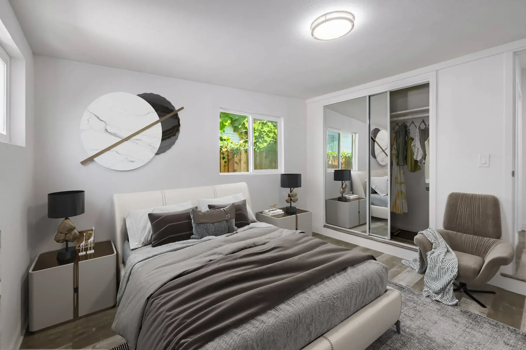 Bedroom with a round wall clock, mirrored closet doors and an upholstered bed