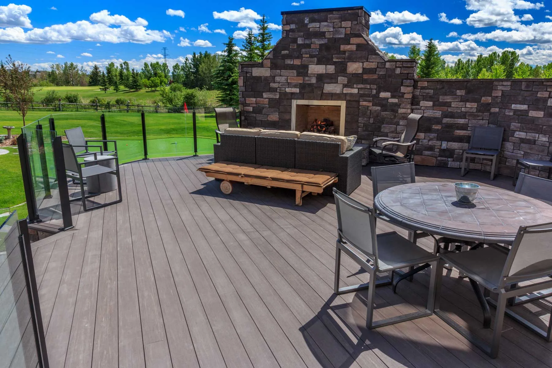 Composite deck with a stone outdoor fireplace overlooking a putting green