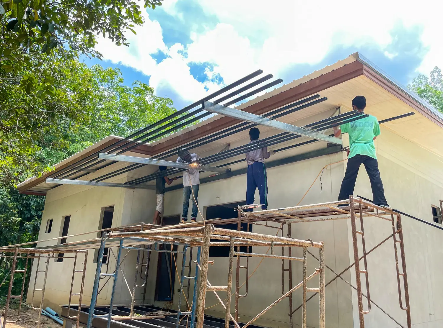 Crew on scaffolding installing roof framing on a house being rebuilt