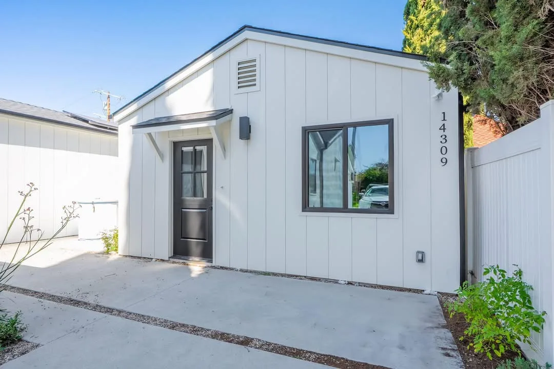 Detached ADU with white board-and-batten siding and a covered entry