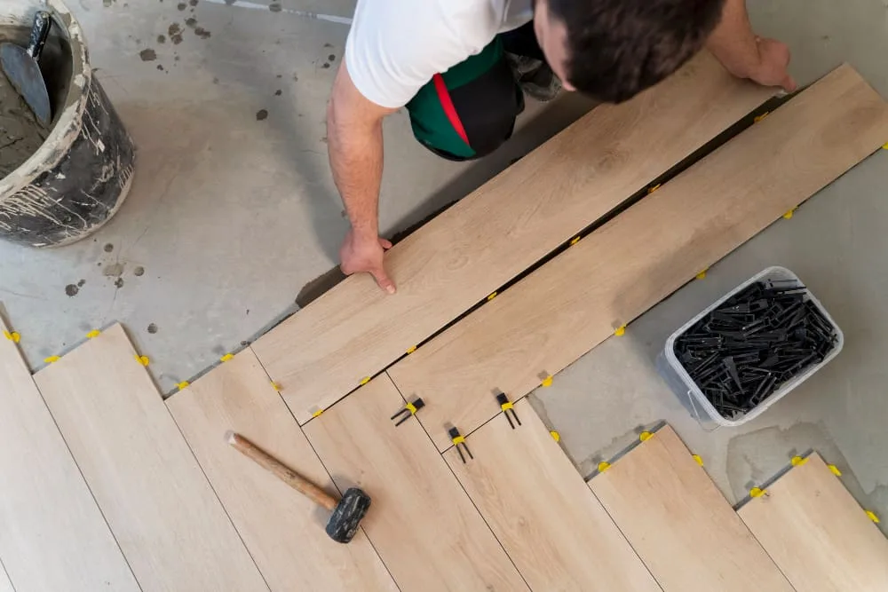 Installer laying light oak laminate planks with spacers