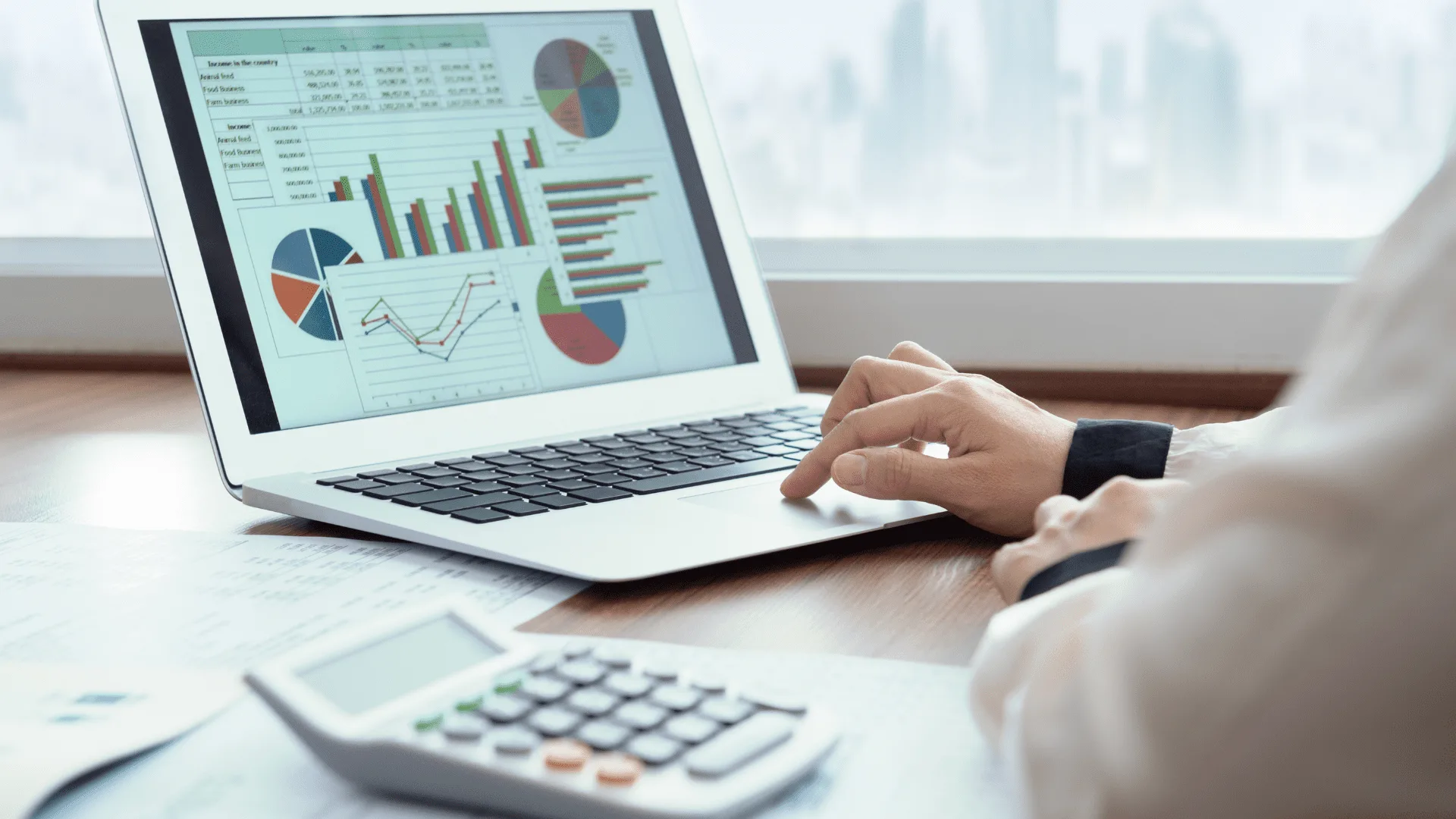 Laptop showing cost report charts beside a calculator