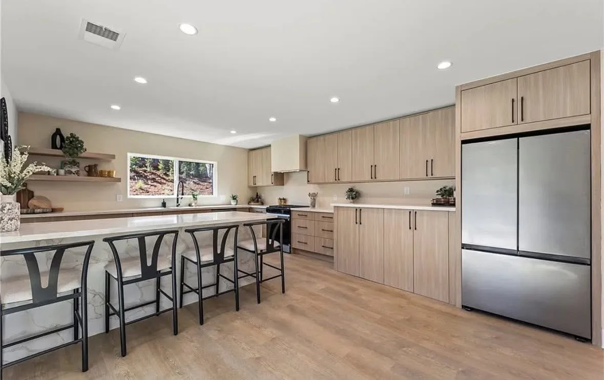 Light oak kitchen with a quartz island and black stools