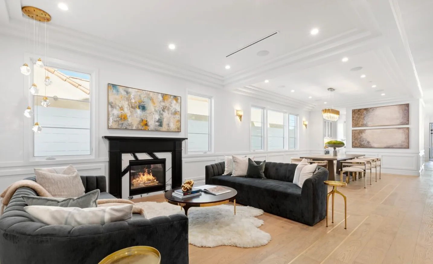 Whole-home design and build: open living and dining room with a black marble fireplace, velvet sofas and brass lighting
