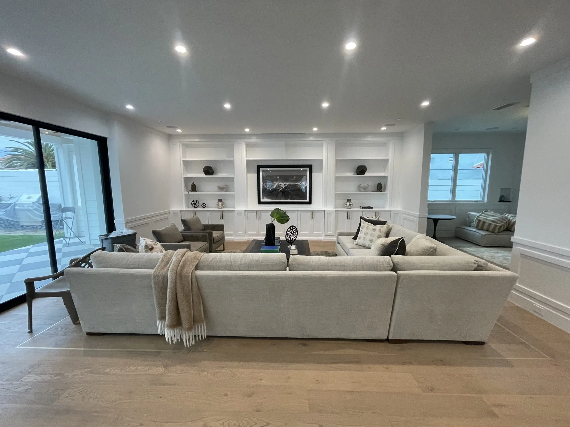 Full remodel living room with white built-in shelving, a sectional sofa and a coffered ceiling