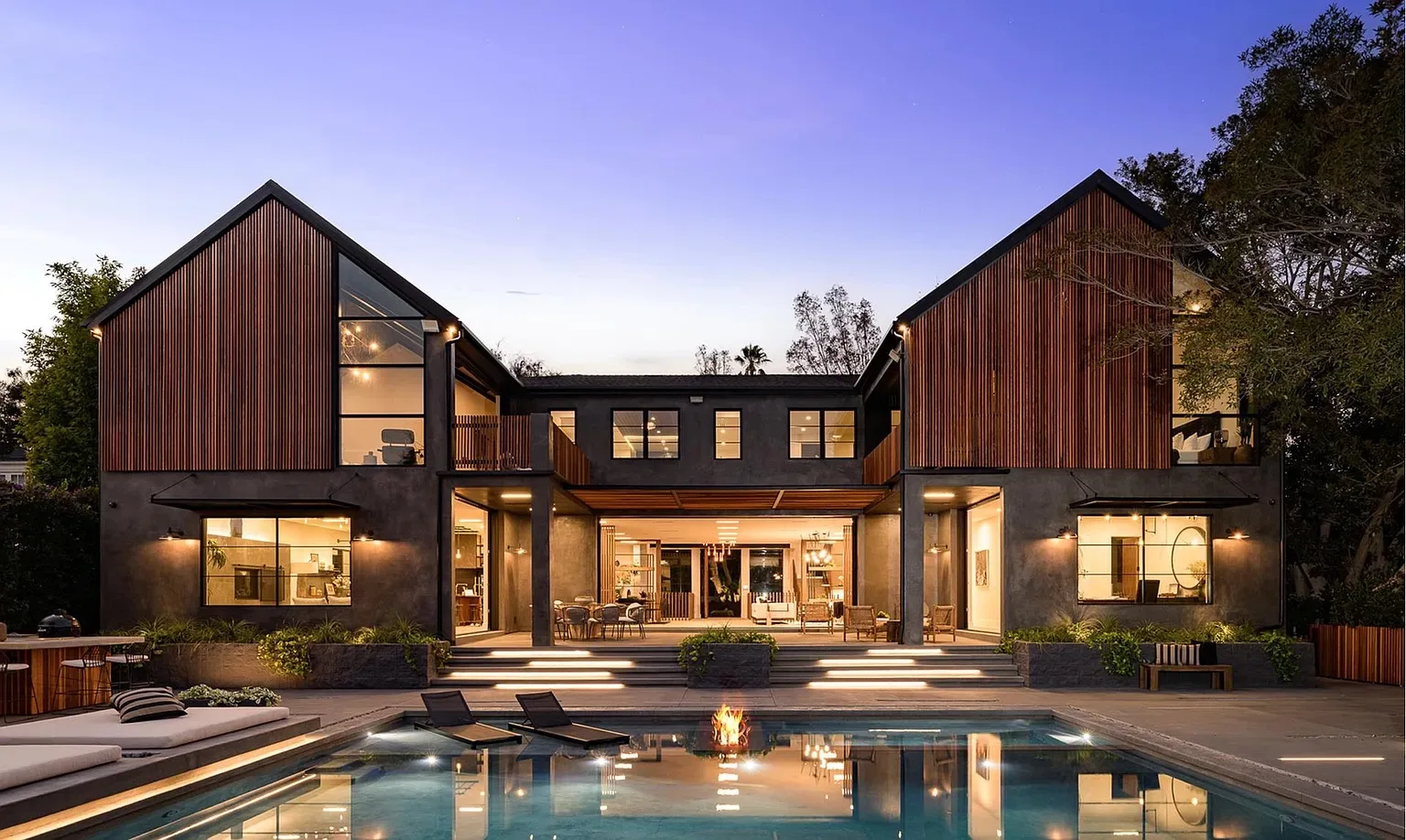 Luxury Los Angeles home renovation with timber cladding and a lit pool at dusk