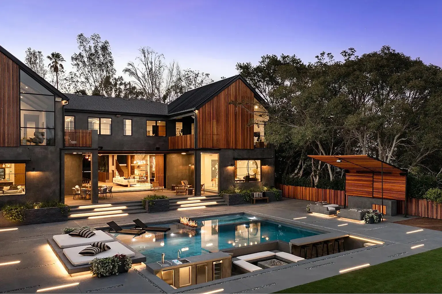 Full property transformation: modern home at dusk with a pool, sunken fire pit lounge and cabana