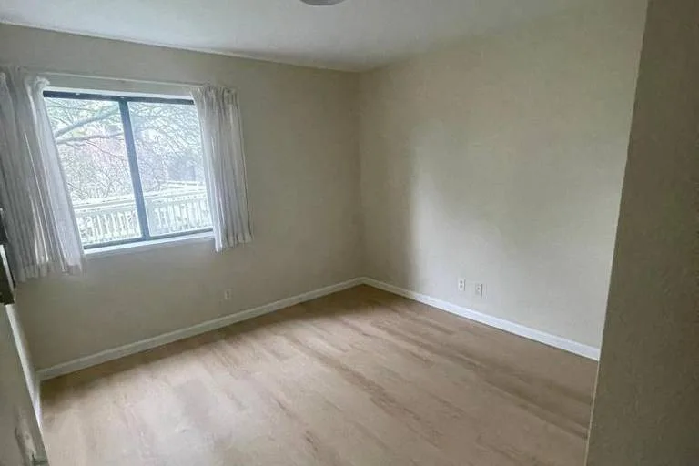 Refreshed bedroom with new light wood-look flooring, white baseboards and fresh paint at 1004 Saddleback Dr, San Francisco
