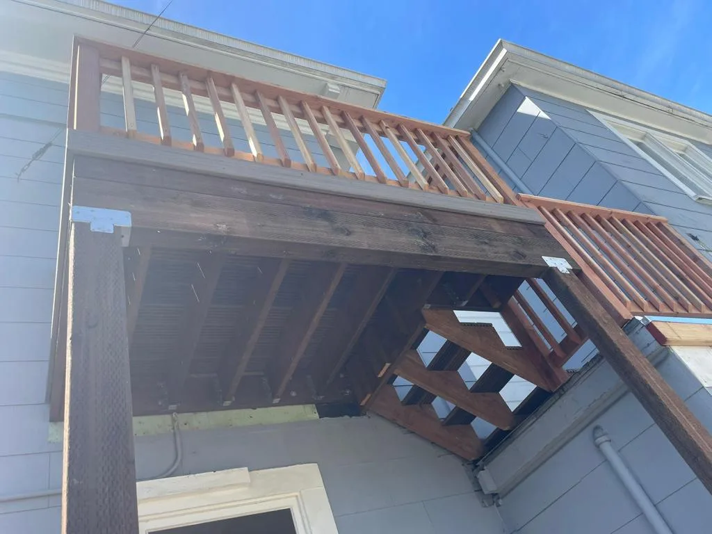 View from below of a new timber deck with wood railings and stair framing at 2015 Clinton Ave, Alameda