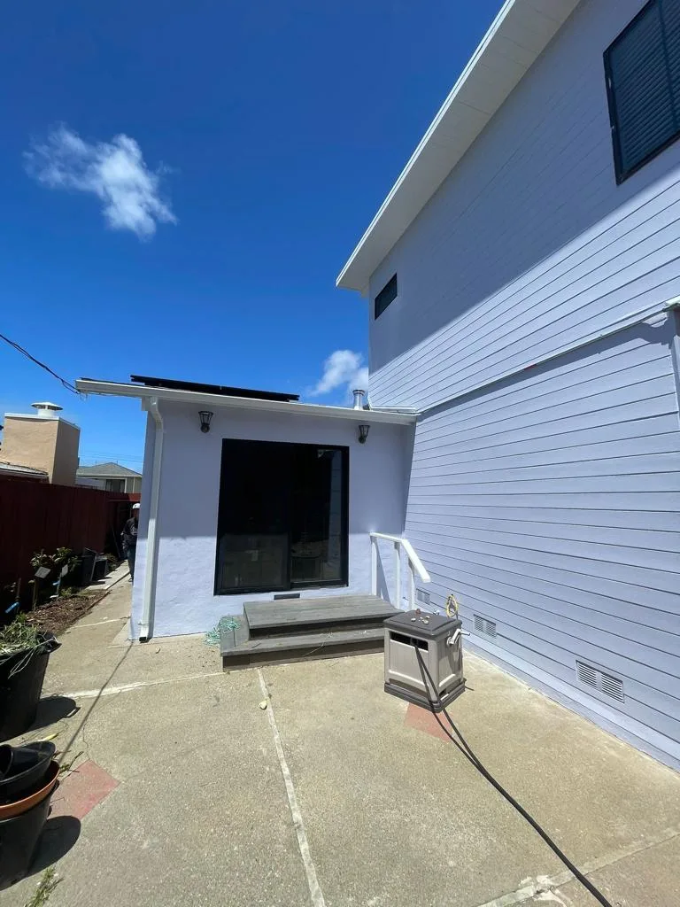Side yard of the light blue sided house with a small rear structure and a black-framed window at 346 Evergreen Dr, San Francisco