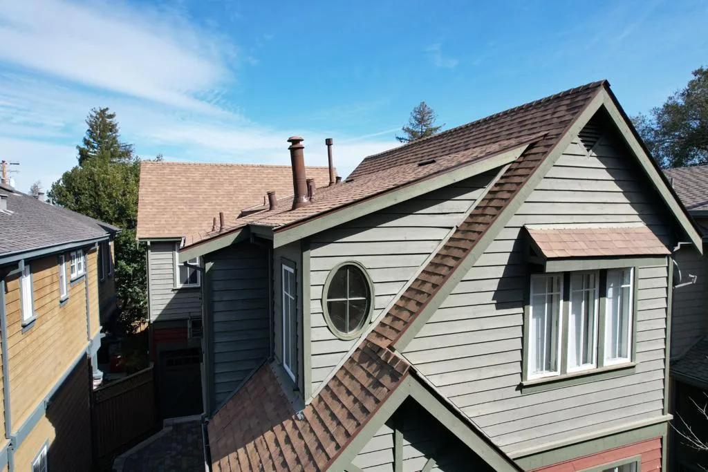 Two-storey home with grey siding, a round window and a new brown shingle roof at 4105 Wisteria Ln, Palo Alto