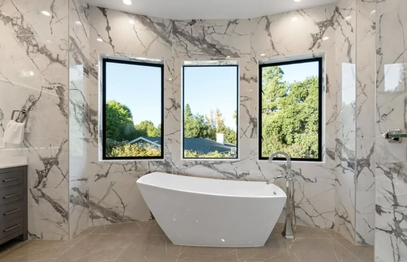 Marble-look bathroom with a freestanding tub under three black-framed windows on E Sierra Madre Blvd, Sierra Madre