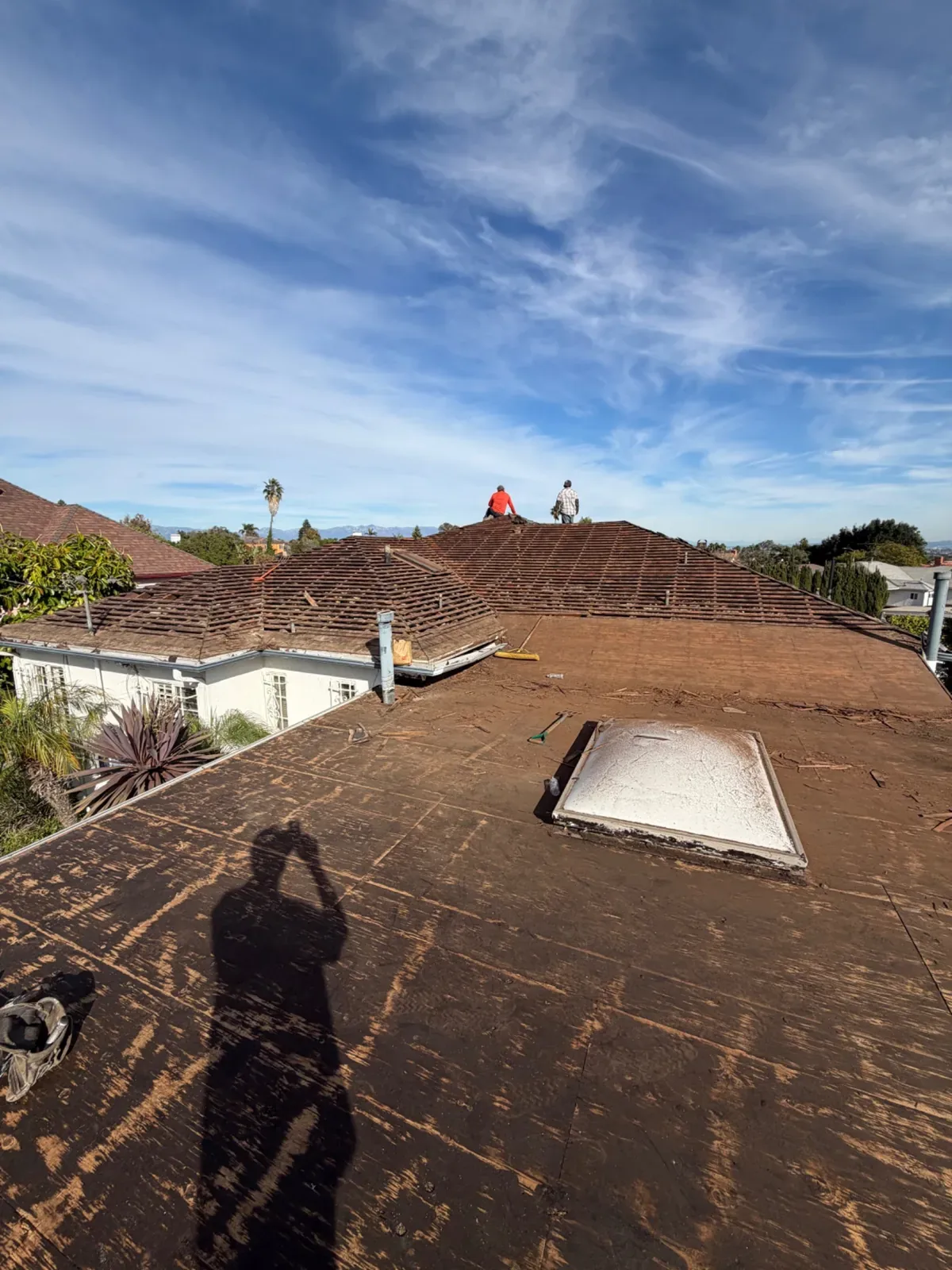 Roof tear-off with the old roofing stripped back to the deck around a skylight