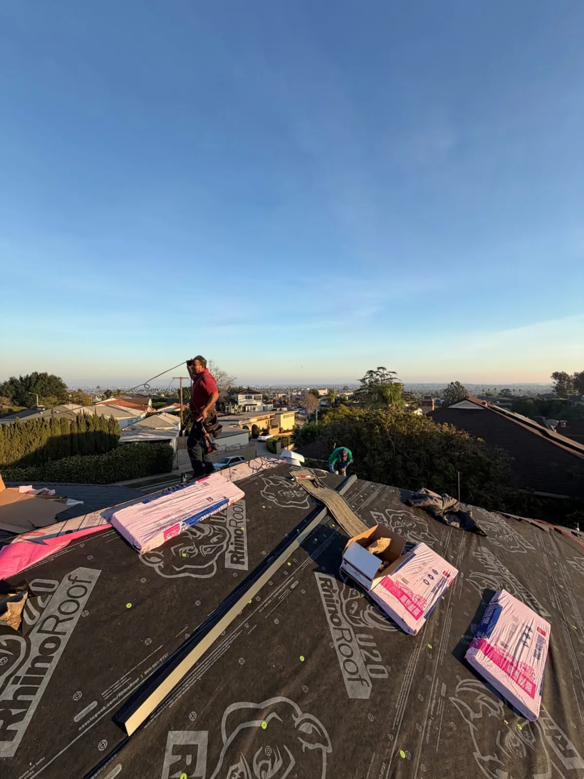 New underlayment on the roof deck with shingle bundles staged at sunset