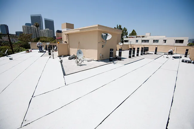 White flat roof membrane with city towers in the background