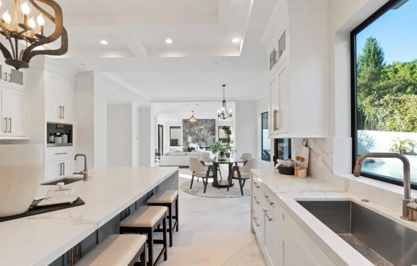 Kitchen remodel with a marble island, brass fixtures and a black-framed window over the sink